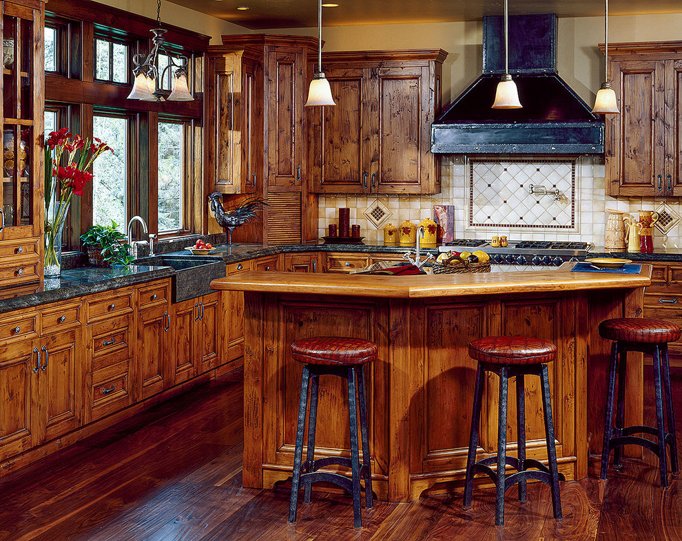 Mid-sized mountain style l-shaped dark wood floor eat-in kitchen photo with a farmhouse sink, recessed-panel cabinets, dark wood cabinets, granite countertops, beige backsplash, ceramic backsplash, stainless steel appliances and an island