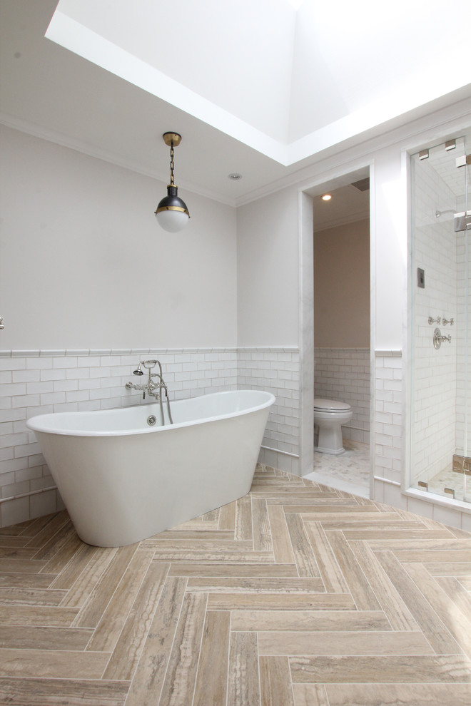 Design ideas for a large traditional master bathroom in New York with flat-panel cabinets, light wood cabinets, a freestanding tub, an alcove shower, white tile, subway tile, white walls, travertine floors, an undermount sink and marble benchtops.