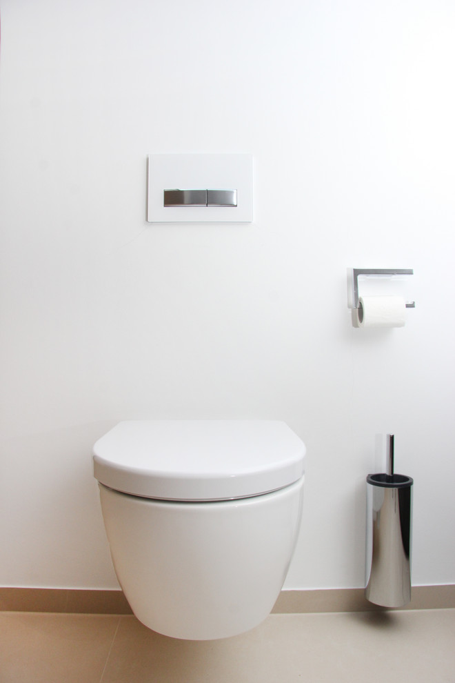 Gästetoilette With flächenbündigen Schrankfronten, schwarzen Schränken, Duschnische, Wandtoilette, beigen Fliesen, Steinfliesen, beiger Wandfarbe, Wandwaschbecken, Mineralwerkstoff-Waschtisch, beigem Boden, offener Dusche and weißer Waschtischplatte in Munich
