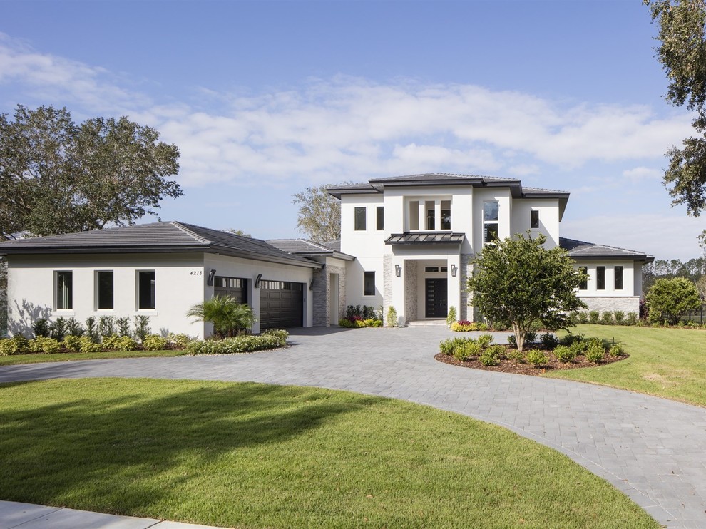 Large transitional two-storey stucco white house exterior in Orlando with a tile roof and a gable roof.