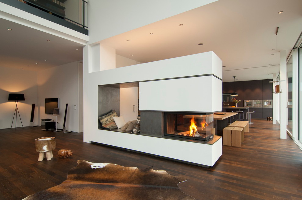 This is an example of a large contemporary formal open concept living room in Munich with white walls, dark hardwood floors, a concrete fireplace surround and a two-sided fireplace.