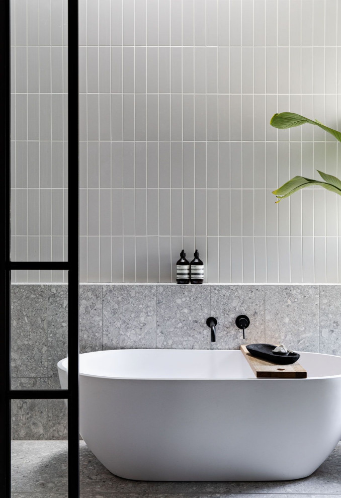 На фото: ванная комната в стиле лофт с белыми фасадами, отдельно стоящей ванной, серой плиткой, керамической плиткой, серыми стенами, полом из керамогранита, столешницей из плитки, серым полом, нишей и тумбой под две раковины