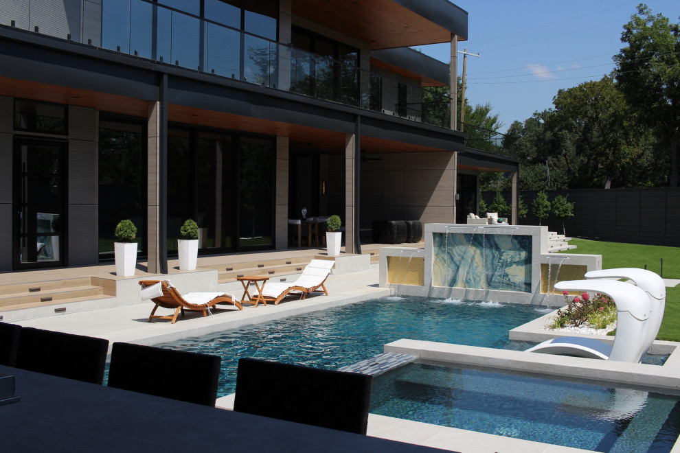 Example of a large minimalist backyard rectangular lap pool fountain design in Dallas with decking