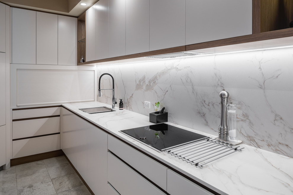 This is an example of a modern kitchen in Perth with flat-panel cabinets, white cabinets, quartz benchtops, grey splashback, marble splashback, black appliances and grey benchtop.