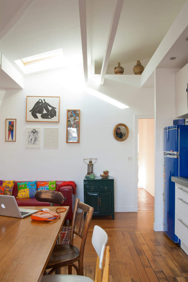 Photo of a mid-sized contemporary kitchen/dining combo in Paris with white walls and medium hardwood floors.