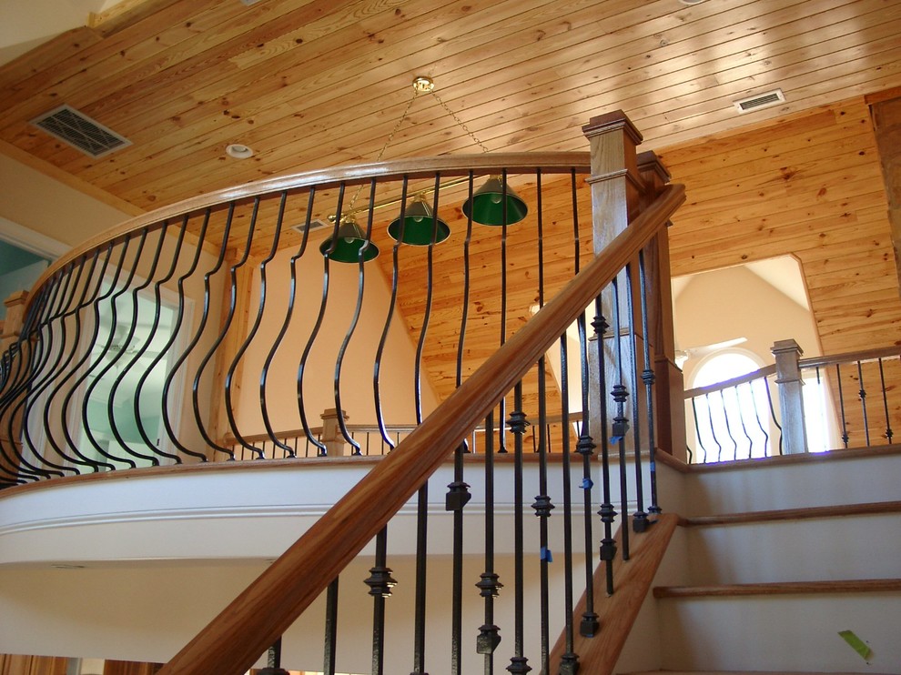 Large country wood curved staircase in Raleigh with painted wood risers.