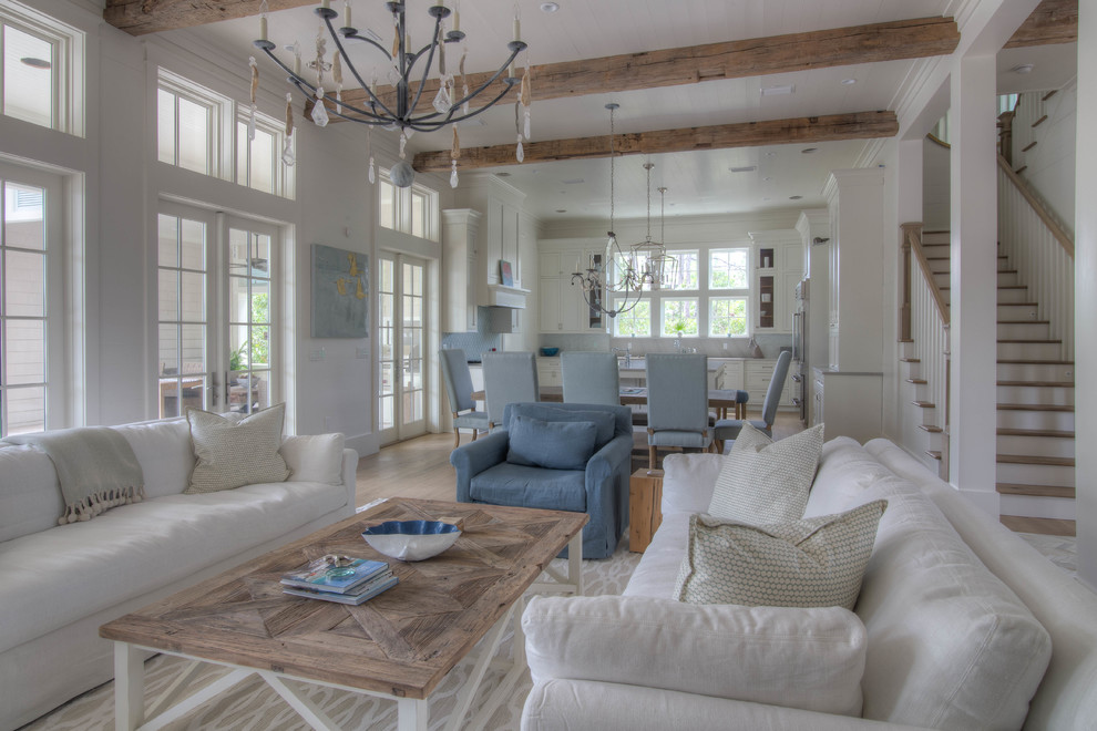 Inspiration for an expansive beach style open concept living room in Atlanta with white walls, light hardwood floors, a standard fireplace, a brick fireplace surround, a wall-mounted tv and beige floor.
