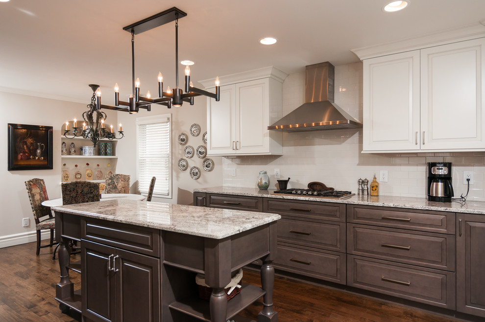 This is an example of a traditional u-shaped eat-in kitchen in Detroit with a farmhouse sink, raised-panel cabinets, granite benchtops, white splashback, subway tile splashback, stainless steel appliances, medium hardwood floors and with island.