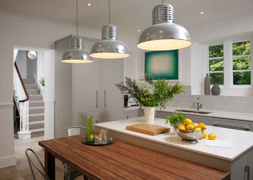 Mid-sized country eat-in kitchen in Other with a double-bowl sink, flat-panel cabinets, grey cabinets, solid surface benchtops, subway tile splashback, stainless steel appliances, porcelain floors, with island and grey splashback.
