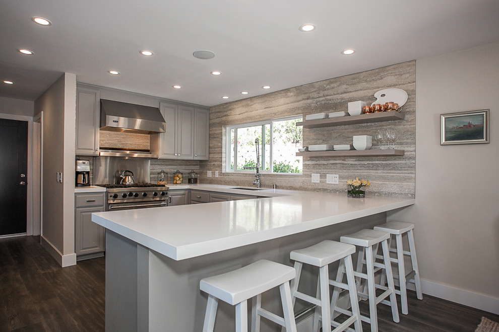 This is an example of a transitional kitchen in Orange County with grey cabinets, quartzite benchtops, stone tile splashback, stainless steel appliances, an undermount sink and dark hardwood floors.