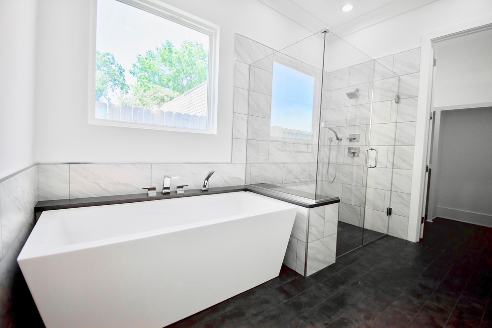 Photo of a transitional master bathroom in New Orleans with shaker cabinets, white cabinets, a freestanding tub, a curbless shower, a two-piece toilet, white tile, porcelain tile, white walls, porcelain floors, an undermount sink, engineered quartz benchtops, grey floor, a hinged shower door and grey benchtops.