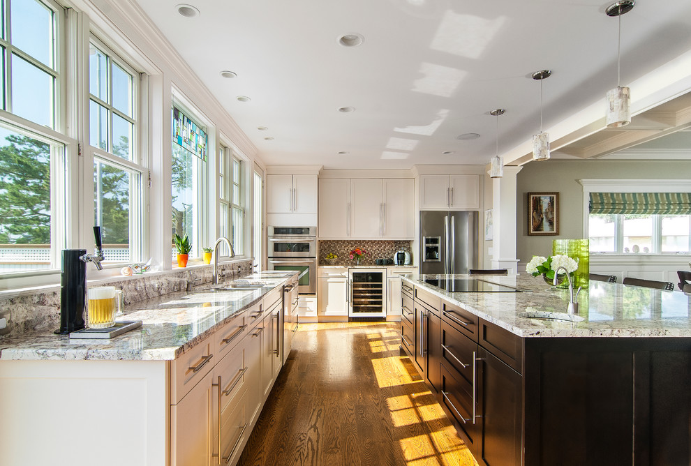 Large transitional l-shaped medium tone wood floor eat-in kitchen photo with recessed-panel cabinets, white cabinets, granite countertops, gray backsplash, stainless steel appliances and an island