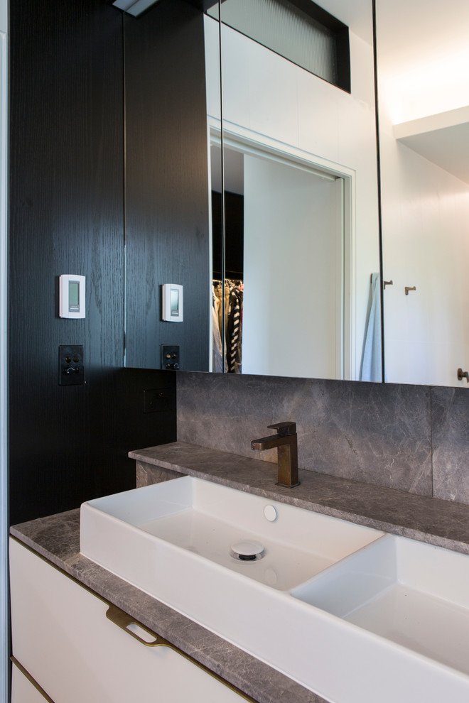 This is an example of a contemporary bathroom in Central Coast with furniture-like cabinets, white cabinets, a vessel sink and marble benchtops.