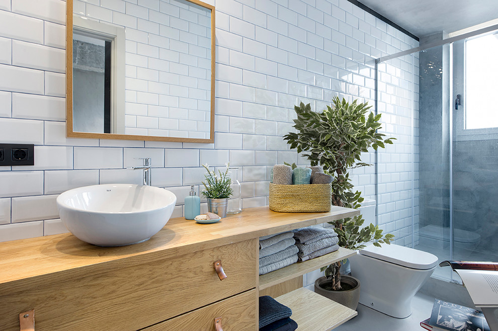 Inspiration for a mid-sized industrial 3/4 bathroom in Barcelona with flat-panel cabinets, medium wood cabinets, an alcove shower, a two-piece toilet, white tile, subway tile, a vessel sink and wood benchtops.