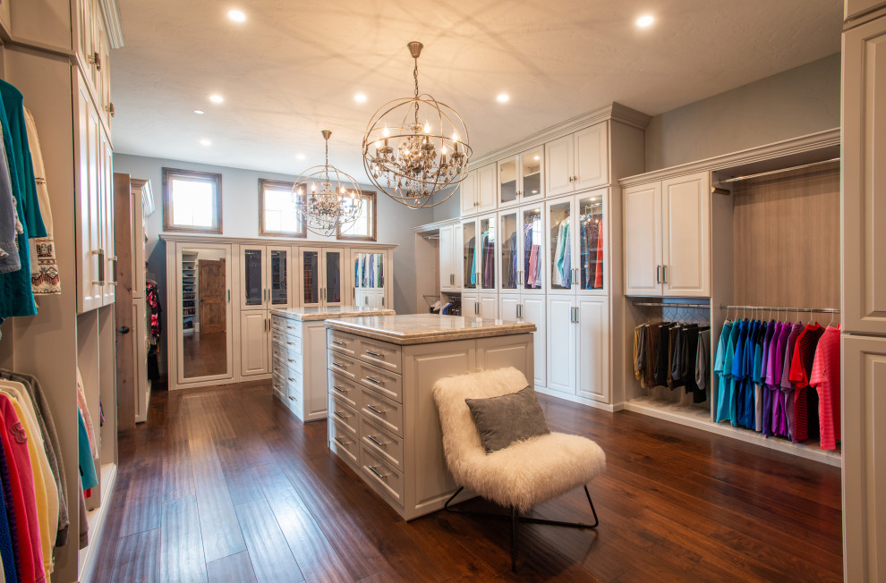Large transitional gender-neutral dressing room in Denver with raised-panel cabinets, grey cabinets, dark hardwood floors, brown floor and vaulted.