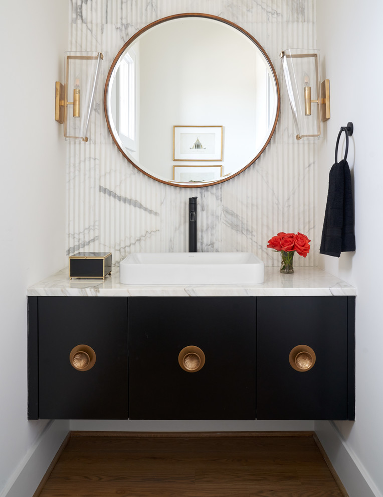 This is an example of a transitional powder room in Dallas with flat-panel cabinets, black cabinets, white tile, white walls, medium hardwood floors, a drop-in sink, brown floor and white benchtops.