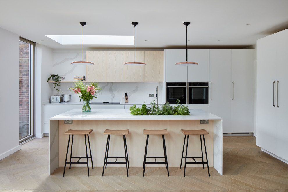 Design ideas for a large scandinavian l-shaped kitchen in London with flat-panel cabinets, white cabinets, quartzite benchtops, white splashback, with island, white benchtop, black appliances, light hardwood floors and beige floor.