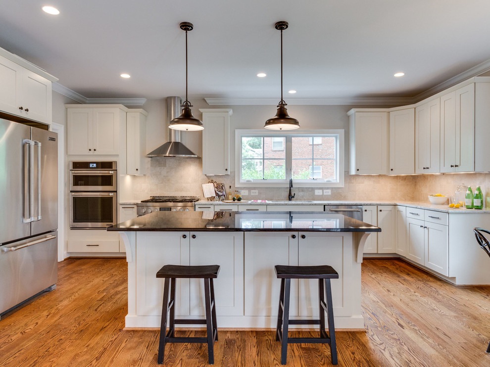 Traditional l-shaped kitchen in DC Metro with shaker cabinets, white cabinets, beige splashback, stainless steel appliances, light hardwood floors and with island.