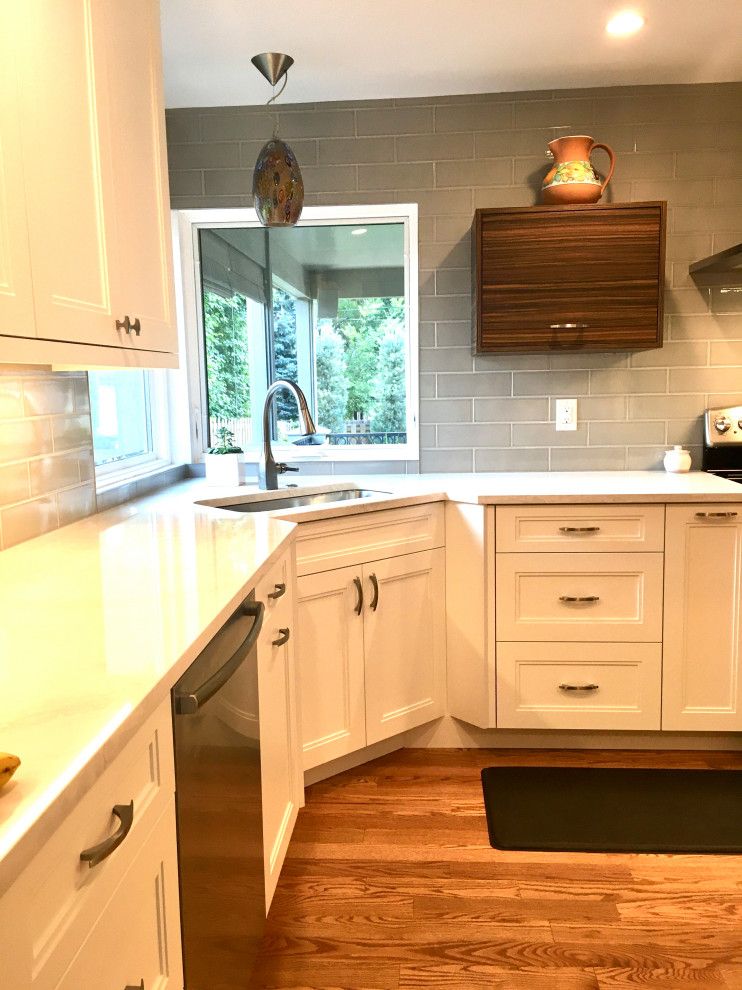 Inspiration for a small transitional u-shaped medium tone wood floor and brown floor enclosed kitchen remodel in Denver with a drop-in sink, shaker cabinets, white cabinets, quartz countertops, gray backsplash, subway tile backsplash, stainless steel appliances, a peninsula and white countertops