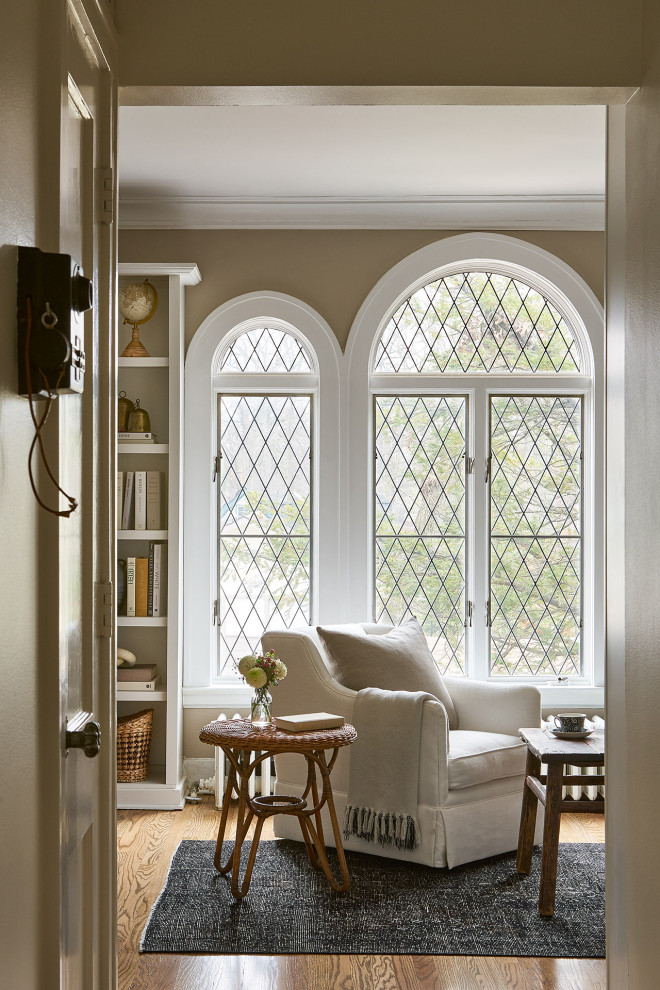 Foto di un soggiorno classico di medie dimensioni e aperto con libreria, pareti beige, pavimento in legno massello medio, TV a parete e pavimento marrone