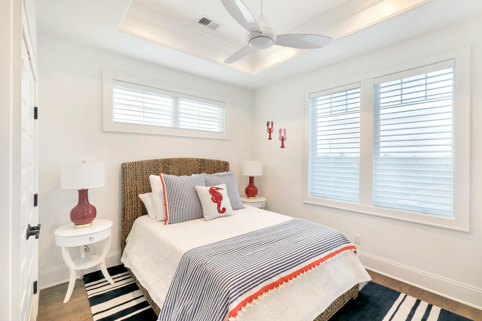 Photo of a beach style guest bedroom in New York with white walls and medium hardwood floors.