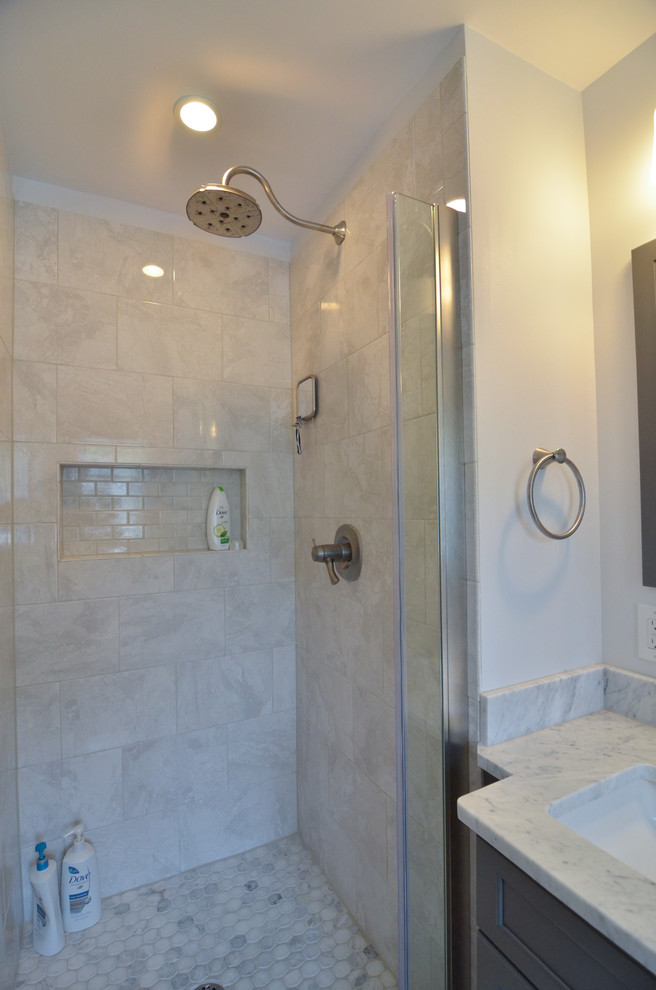 This is an example of a mid-sized transitional master bathroom in Philadelphia with an undermount sink, shaker cabinets, grey cabinets, marble benchtops, an alcove shower, a two-piece toilet, gray tile, ceramic tile, white walls and ceramic floors.