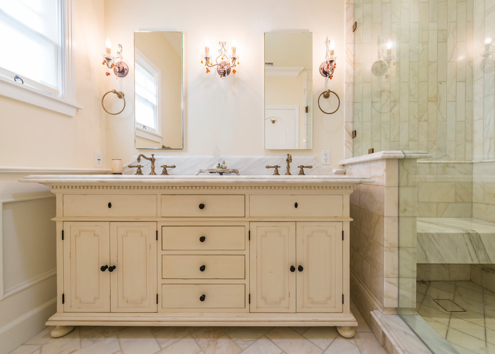 Design ideas for a mid-sized traditional master bathroom in Los Angeles with recessed-panel cabinets, distressed cabinets, an alcove shower, beige tile, marble, beige walls, marble floors, an undermount sink, marble benchtops, beige floor and a hinged shower door.