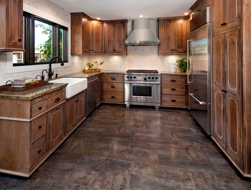 Inspiration for a mid-sized transitional u-shaped separate kitchen in Santa Barbara with a farmhouse sink, raised-panel cabinets, medium wood cabinets, granite benchtops, beige splashback, mosaic tile splashback, stainless steel appliances, ceramic floors and no island.