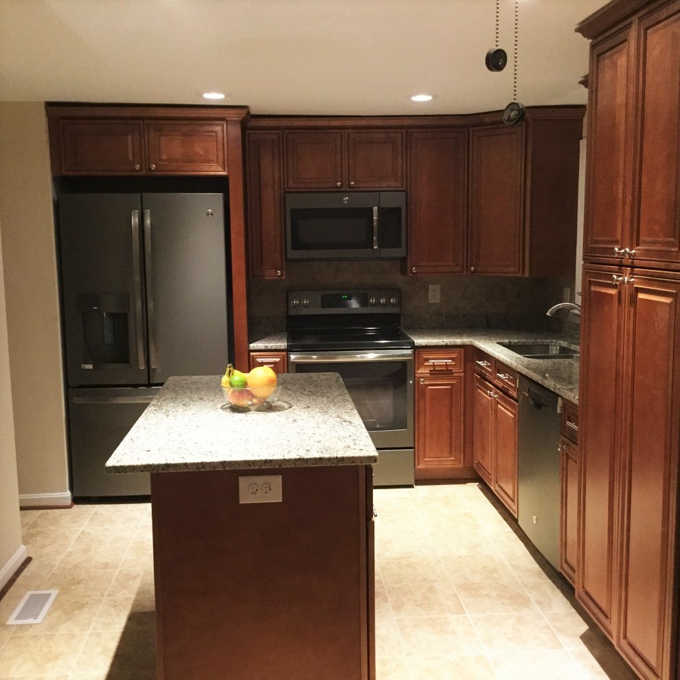 Inspiration for a large transitional l-shaped porcelain tile eat-in kitchen remodel in DC Metro with an undermount sink, raised-panel cabinets, medium tone wood cabinets, granite countertops, beige backsplash, porcelain backsplash, stainless steel appliances and an island