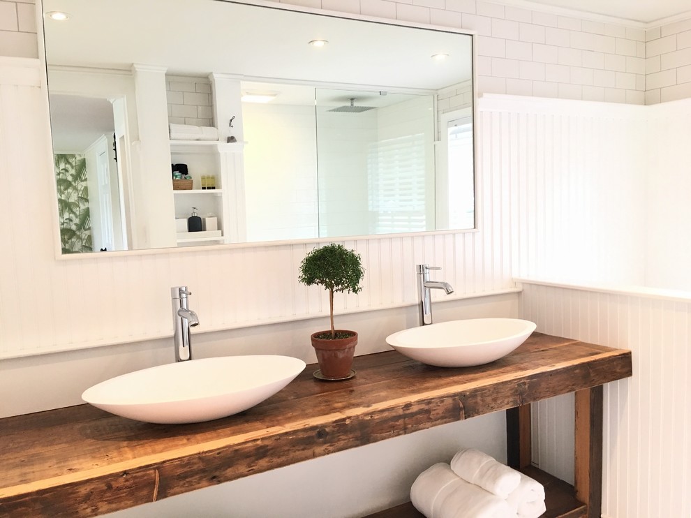 Photo of a large country master bathroom in Providence with open cabinets, distressed cabinets, an open shower, a one-piece toilet, white tile, subway tile, white walls, painted wood floors, a vessel sink, wood benchtops, black floor and an open shower.