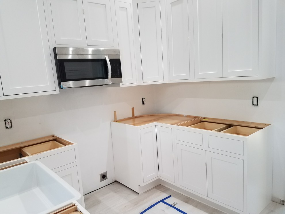 Inspiration for a mid-sized transitional u-shaped laminate floor and white floor kitchen remodel in Miami with a farmhouse sink, flat-panel cabinets, white cabinets, marble countertops, white backsplash, cement tile backsplash, stainless steel appliances, an island and white countertops