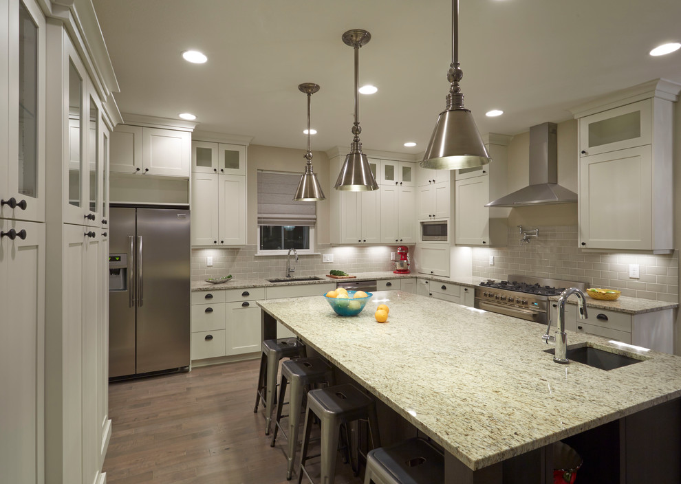 Example of a large transitional u-shaped medium tone wood floor eat-in kitchen design in Denver with an undermount sink, shaker cabinets, white cabinets, laminate countertops, green backsplash, ceramic backsplash, stainless steel appliances and an island