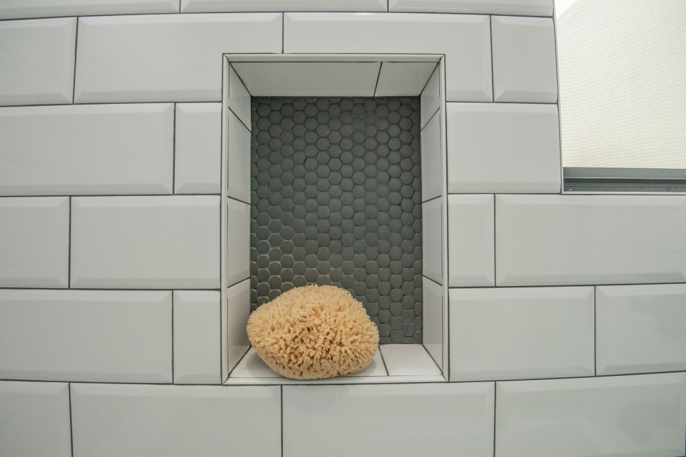 Пример оригинального дизайна: ванная комната среднего размера в современном стиле с фасадами с филенкой типа жалюзи, белыми фасадами, ванной в нише, душем над ванной, раздельным унитазом, белой плиткой, плиткой кабанчик, серыми стенами, полом из цементной плитки, душевой кабиной, врезной раковиной, столешницей из искусственного кварца, серым полом, душем с распашными дверями, белой столешницей, нишей, тумбой под две раковины и напольной тумбой