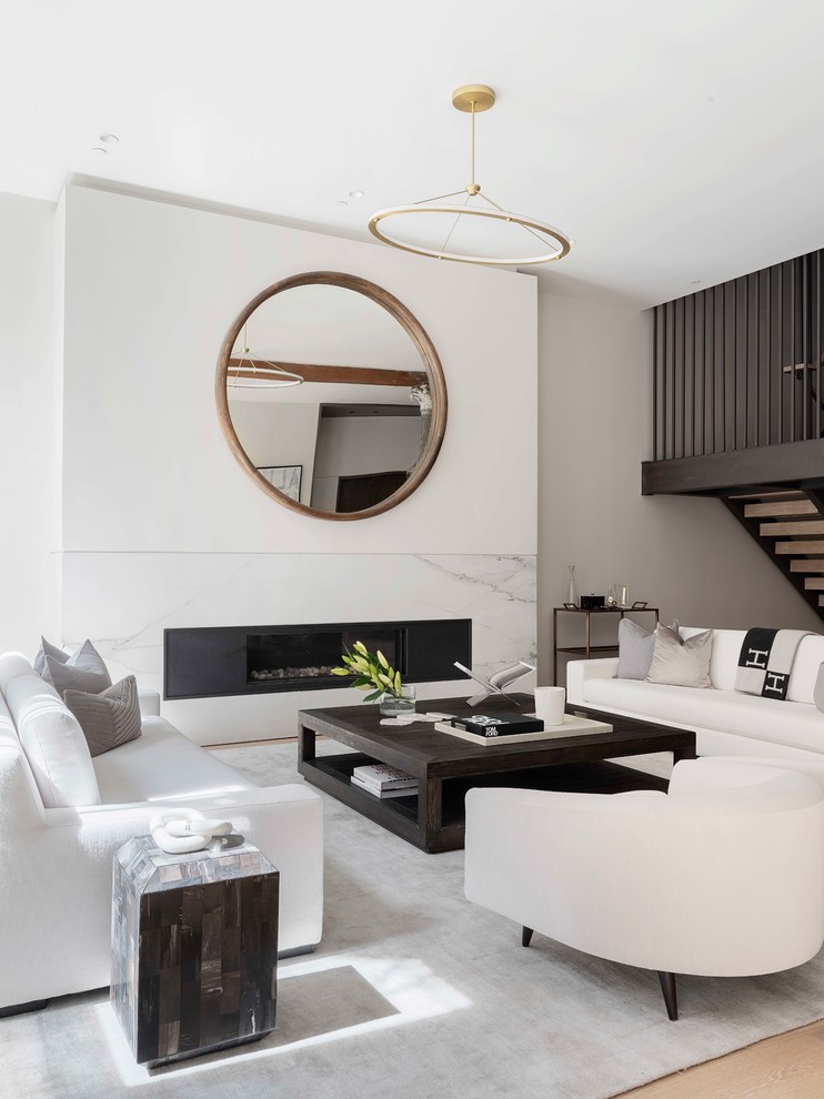 This is an example of a contemporary open concept living room in New York with grey walls, light hardwood floors, a ribbon fireplace, a stone fireplace surround and beige floor.