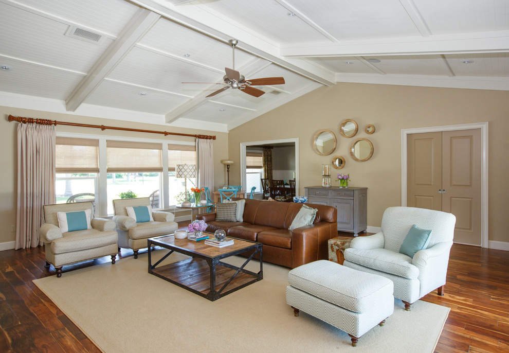 Design ideas for a large beach style open concept living room in Jacksonville with beige walls, medium hardwood floors, a standard fireplace, a tile fireplace surround and a concealed tv.