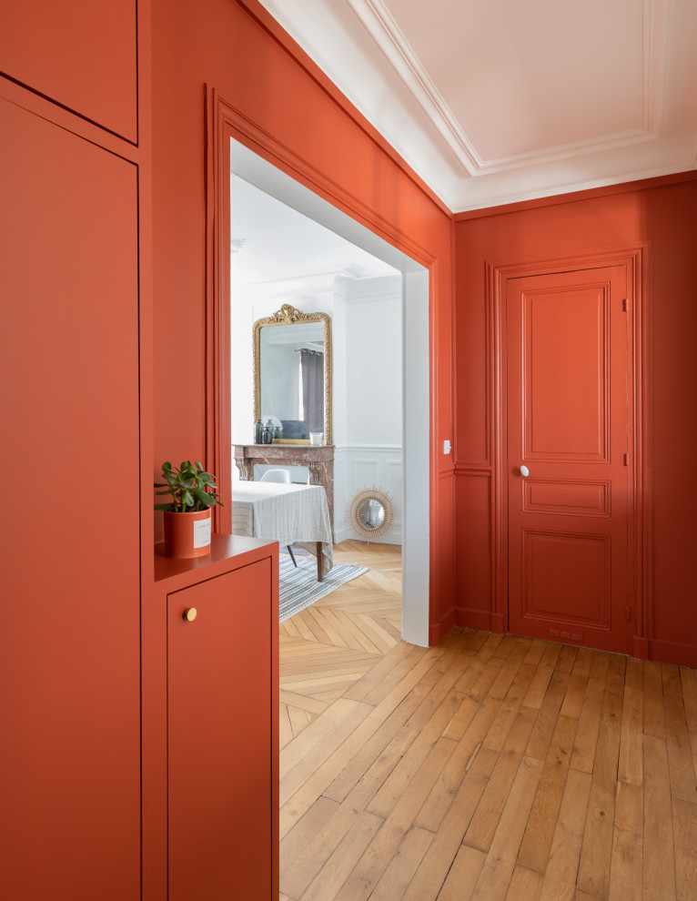 Idée de décoration pour un hall d'entrée minimaliste de taille moyenne avec un mur rouge, un sol en bois brun, un sol marron, une porte simple et une porte rouge.