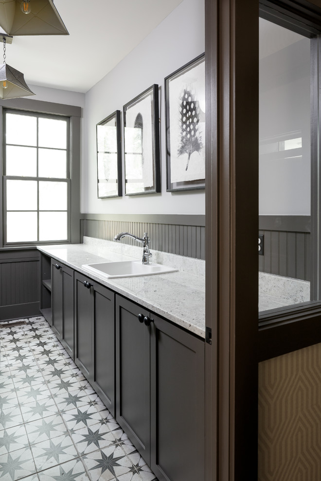 Inspiration for a traditional galley laundry room in Louisville with a drop-in sink, dark wood cabinets, white walls and porcelain floors.