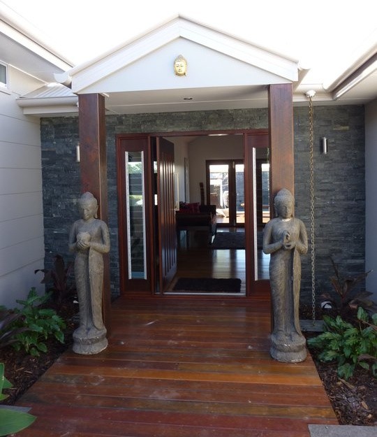 This is an example of an asian front door in Sunshine Coast with dark hardwood floors, a pivot front door and a dark wood front door.
