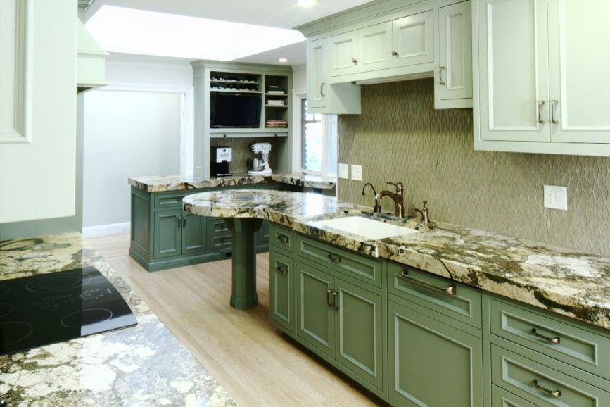 This is an example of a mid-sized galley kitchen pantry in San Francisco with a single-bowl sink, flat-panel cabinets, green cabinets, granite benchtops, brown splashback, glass tile splashback, panelled appliances, light hardwood floors and a peninsula.