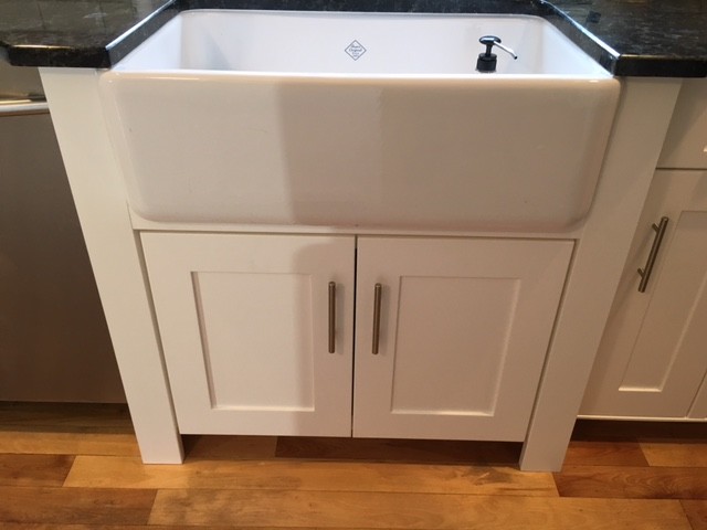 Eat-in kitchen - mid-sized transitional light wood floor eat-in kitchen idea in Boston with a farmhouse sink, recessed-panel cabinets, white cabinets and stainless steel appliances