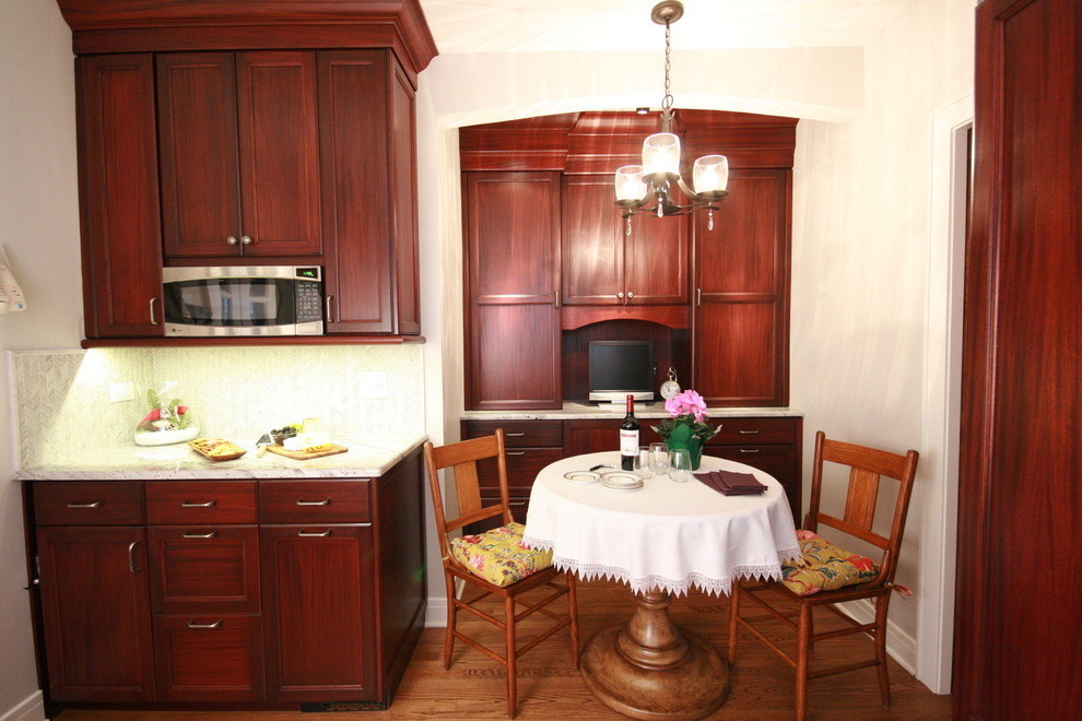 Small elegant u-shaped light wood floor enclosed kitchen photo in Chicago with a drop-in sink, recessed-panel cabinets, dark wood cabinets, granite countertops, multicolored backsplash, mosaic tile backsplash, paneled appliances and no island