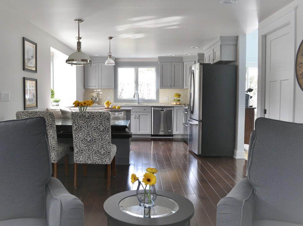 Inspiration for a mid-sized transitional l-shaped dark wood floor and brown floor open concept kitchen remodel in New York with an undermount sink, shaker cabinets, gray cabinets, quartzite countertops, white backsplash, ceramic backsplash, stainless steel appliances and a peninsula