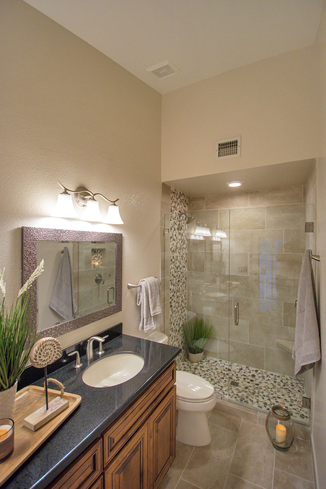 Design ideas for a mid-sized traditional master bathroom in Phoenix with beige tile, porcelain tile, beige walls, porcelain floors, beige floor, a hinged shower door, raised-panel cabinets, dark wood cabinets, an alcove shower, a two-piece toilet, an undermount sink and engineered quartz benchtops.
