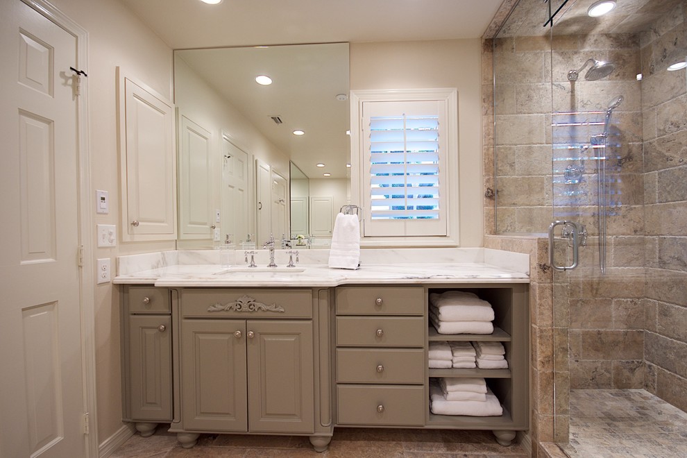 Photo of a large contemporary master bathroom in Austin with shaker cabinets, green cabinets, a freestanding tub, an alcove shower, a two-piece toilet, beige tile, travertine, beige walls, travertine floors, an undermount sink, marble benchtops, beige floor and a hinged shower door.