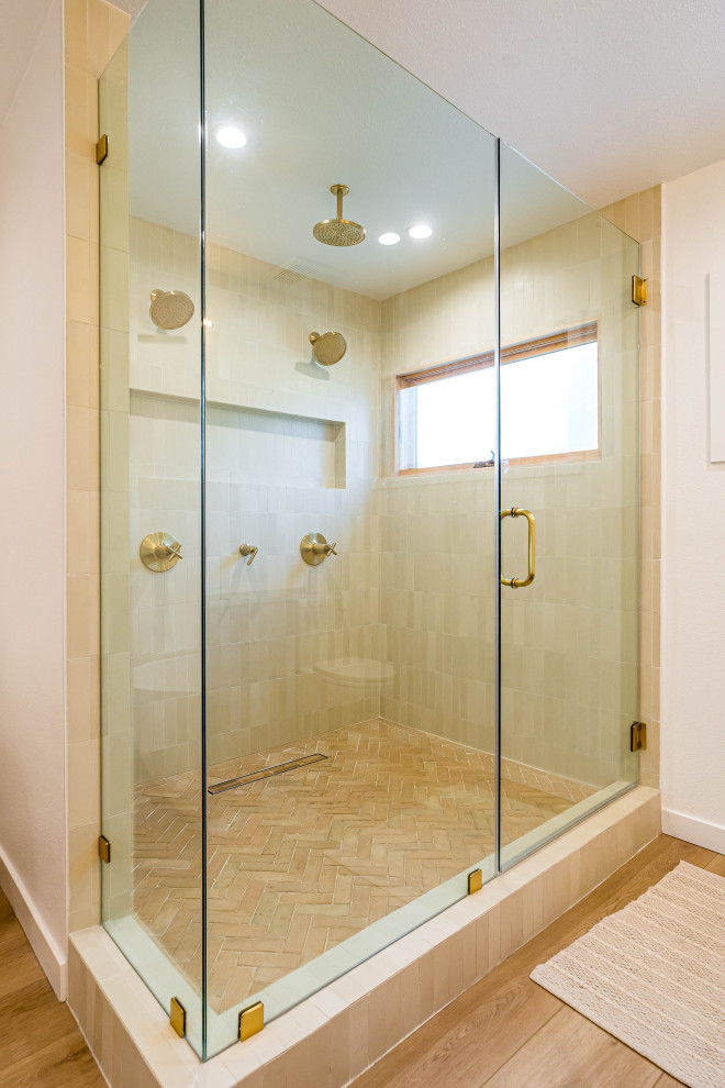 Inredning av ett modernt brun brunt badrum, med luckor med lamellpanel, bruna skåp, ett fristående badkar, en dusch i en alkov, en toalettstol med hel cisternkåpa, beige kakel, keramikplattor, vita väggar, ljust trägolv, ett fristående handfat, marmorbänkskiva, brunt golv och dusch med gångjärnsdörr