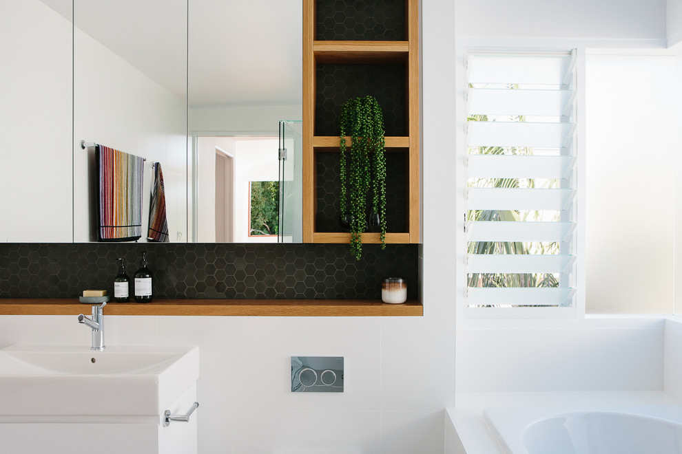 Inspiration for a contemporary bathroom in Other with flat-panel cabinets, white cabinets, a drop-in tub, white tile, white walls and a console sink.