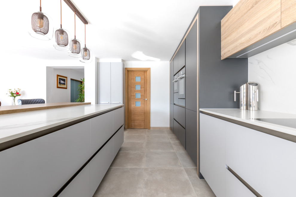 Inspiration for a mid-sized contemporary l-shaped open plan kitchen in Sussex with flat-panel cabinets, grey cabinets, solid surface benchtops, stainless steel appliances, with island and white benchtop.