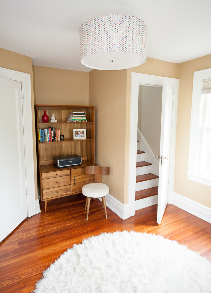 This is an example of a small transitional study room in New York with beige walls, light hardwood floors and a freestanding desk.