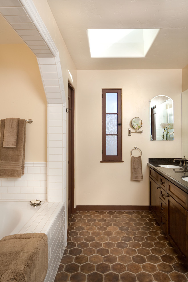 Inspiration for a mid-sized mediterranean master bathroom in Los Angeles with brown tile, beige walls, terra-cotta floors, shaker cabinets, dark wood cabinets, an undermount sink, an alcove tub, a corner shower and brown floor.