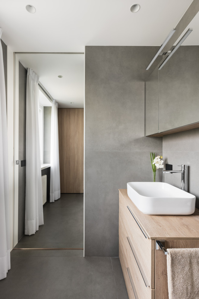 This is an example of a small contemporary bathroom in Rome with flat-panel cabinets, light wood cabinets, a two-piece toilet, gray tile, porcelain tile, grey walls, porcelain floors, a vessel sink, laminate benchtops, grey floor, beige benchtops, a laundry, a single vanity and a freestanding vanity.